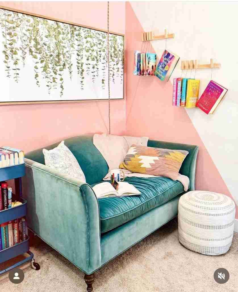 book nook ideas - pink wall and turquoise sofa with books hanging on the wall